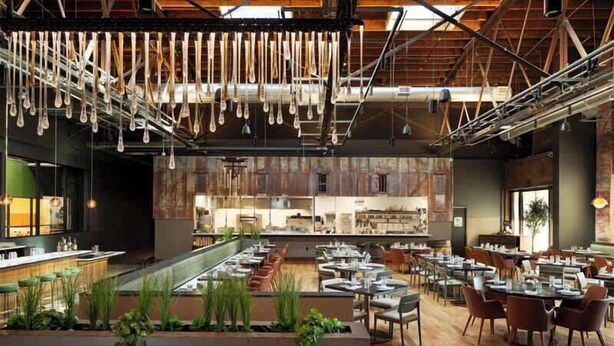 A modern restaurant with a long counter, multiple tables, and hanging light fixtures. - Stylish 3-Bed Retreat, Rooftop, Parking, Sleeps 10  |  Ensuite Baths, Bunk Room, Gourmet Kitchen, Cozy Living Space, Rooftop Views & Fire Table, Near Downtown, Distilleries & Marathon Village, 24 Hr Hospitality (Nashville)