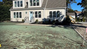 A two-story house with a front porch, a blue door, and a small garden area. - New construction. Short Walk to Beautiful Ridegevale Beach (Chatham)