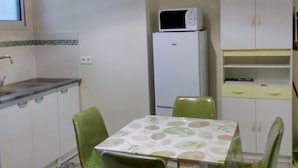 A small kitchen with a dining table and chairs, a refrigerator, a microwave, and a cabinet. - Dépendance Avec Entrée Privée et Terrasse (Fort-de-France)