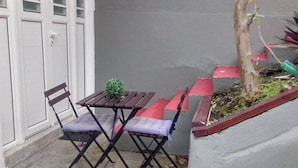 A patio area with a table and chairs, a small potted plant, and a tree. - Dépendance Avec Entrée Privée et Terrasse (Fort-de-France)