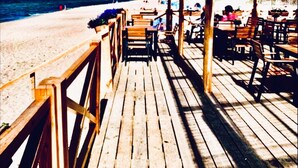 Una terrassa de fusta que condueix a un restaurant a peu de platja, amb seients a l'aire lliure i vistes a l'oceà.