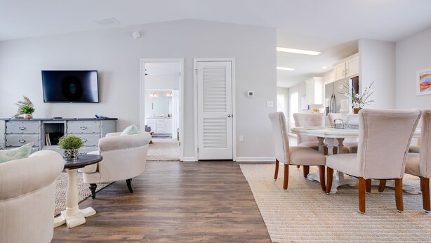 Un salon moderne avec un coin repas, un plancher en bois franc et des murs blancs.