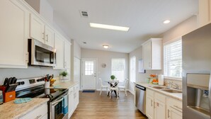 Une cuisine moderne avec des armoires blanches, des appareils en acier inoxydable et un plancher en bois.
