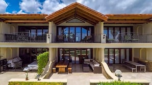 Un bâtiment à deux étages doté d’un balcon, d’un espace extérieur aménagé pour s’asseoir et de grandes fenêtres.