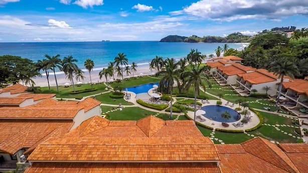 Un complexe hôtelier comprenant plusieurs bâtiments, une piscine et une plage.