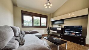 Un salon moderne avec un canapé gris, une table basse noire et un téléviseur.
