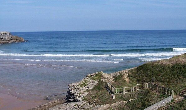 A coastal view with a rocky shoreline, a wooden walkway, and the ocean in the background. - Apartamento en Ajo - Antuerta 12006 (Cantabria)