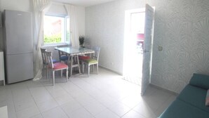 Ein gemütlicher Wohnbereich mit Küchenzeile, einem Esstisch mit Stühlen, einer Couch und einer Wand mit Muster.