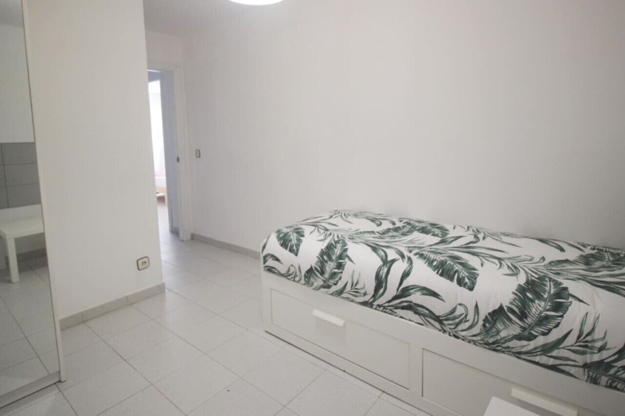 Een slaapkamer met een bed, een witte kast en een deur naar een andere kamer.