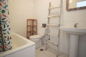 A bathroom with a bathtub, toilet, and a wooden ladder leaning against the wall. - First floor with a terrace in Ajo - Castellanos 12007 (Cantabria)
