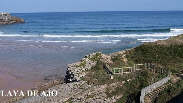 Ein Küstenblick mit felsiger Küstenlinie, einem Holzsteg und dem Meer im Hintergrund.