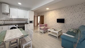 A living room with a sofa, a coffee table, and a TV mounted on the wall.