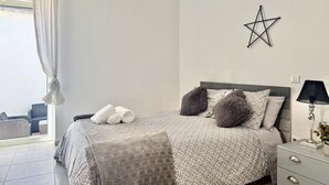 A bedroom with a bed, pillows, a nightstand, a lamp, and a star decoration on the wall.