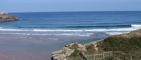 Vista costera con costa rocosa, una pasarela de madera y el océano al fondo.