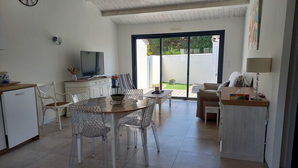 Eine moderne Küche mit Essbereich, einem Fernseher und einer großen Schiebeglastür, die auf eine Terrasse im Freien führt.