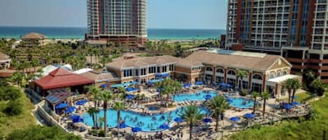 A resort with multiple swimming pools, a beach, and high-rise buildings in the background.