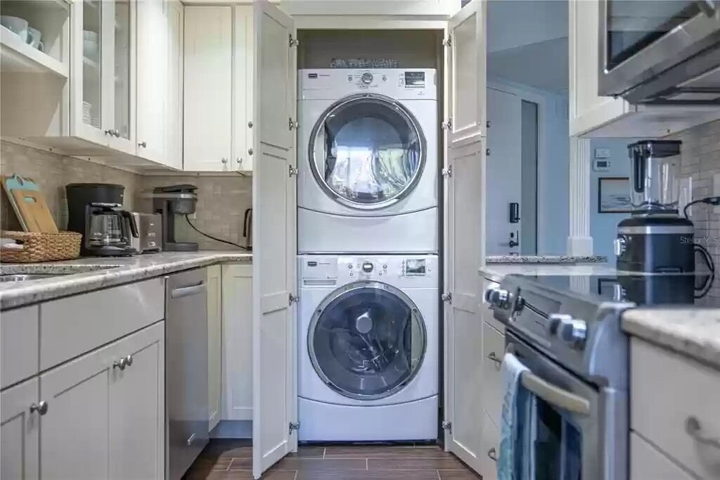 A compact laundry room with two stacked front-loading washing machines, a coffee maker, and a microwave.