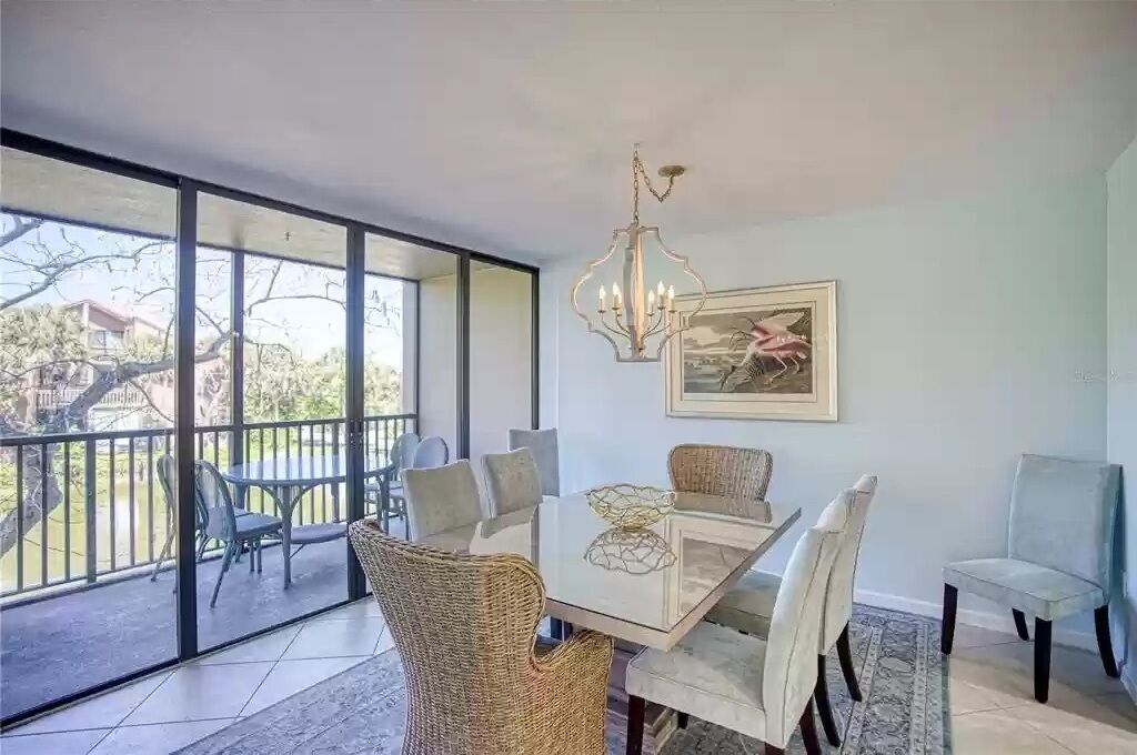A dining area with a glass table, wicker chairs, and a chandelier.