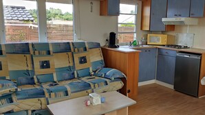 Un espacio habitable pequeño con sofá, una mesita, microondas, lavamanos y una zona de cocina compacta.