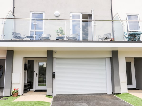 Un immeuble résidentiel de deux étages doté d’un balcon, de portes coulissantes et d’un garage.