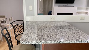 A kitchen with a granite countertop, a black chair, and a ceiling fan.