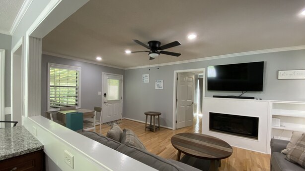 A modern living room with a gray sofa, a wooden coffee table, a fireplace, and a ceiling fan.