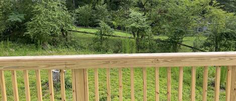 A wooden deck with a view of a lush green landscape and trees in the background.