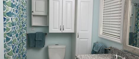 Un baño con inodoro, armarios, lavamanos y cortina de ducha.