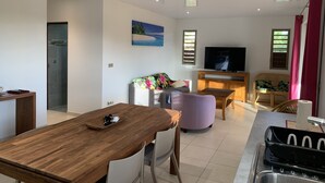 Una sala de estar moderna con una mesa de comedor de madera, un sofá con funda floral, un televisor y un mueble de madera pequeño.