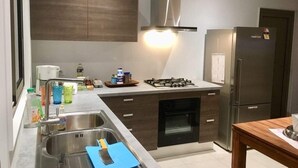 Una cocina moderna con estufa a gas, horno, pileta de acero inoxidable y refrigerador.