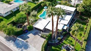 Eine Luftaufnahme eines Wohnhauses mit Swimmingpool, Palmen und einem gepflegten Rasen.