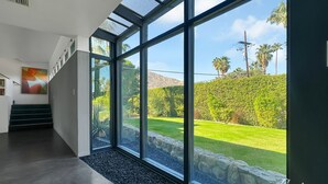 Ein modernes Interieur mit großen Fenstern, einer Treppe und Blick auf einen gepflegten Garten.
