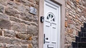 A stone building with a white door marked with the number 3, a small mailbox, and a set of dark tiled stairs leading up to the entrance. - Holiday Lets Penrith – Derwent House (Appleby-In-Westmorland)