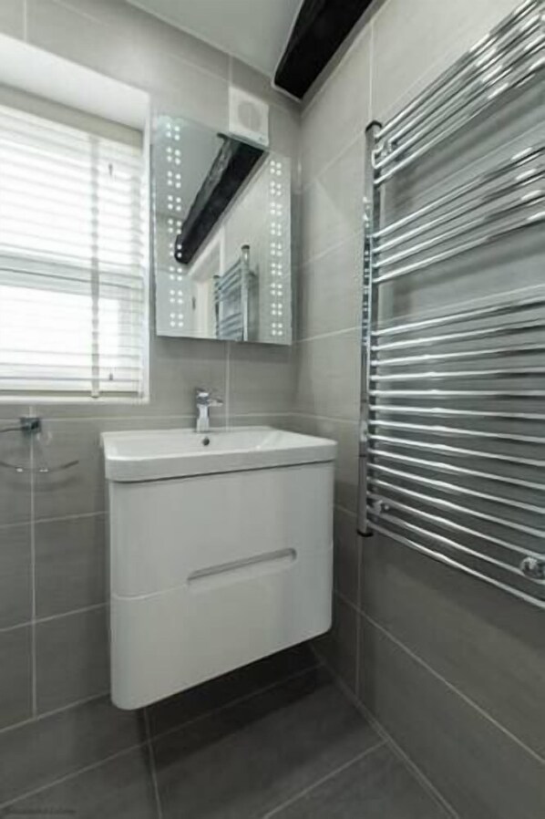 A modern bathroom with a white sink, a mirror above it, and a towel rack on the wall. - Eden Grove Holiday Homes by Guestz (Appleby-In-Westmorland)