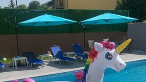 Ein Pool mit einem Einhorn-Schwimmtier und Liegestühlen.