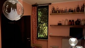 Perinteinen keittiö, jossa on puinen pöytä, riippuvalaisin ja hyllyt, joilla on keittiötarvikkeita.