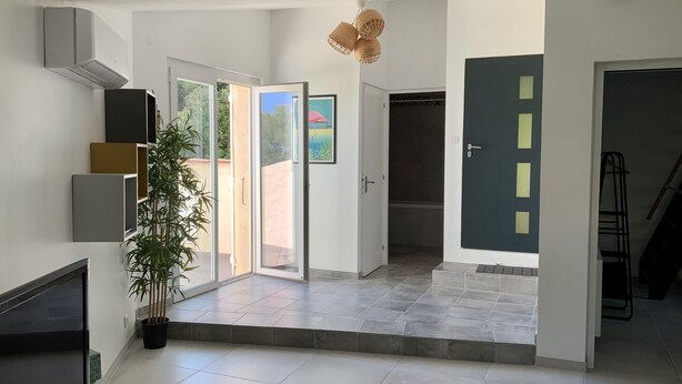 A spacious living area with a flat-screen TV, a potted plant, and a modern staircase leading to another room. - Very nice, quiet apartment near the beach (Hyères)