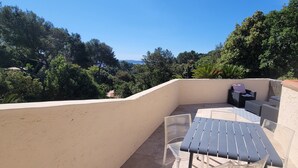 A rooftop terrace with a table and chairs, surrounded by trees and a clear sky. - Very nice, quiet apartment near the beach (Hyères)