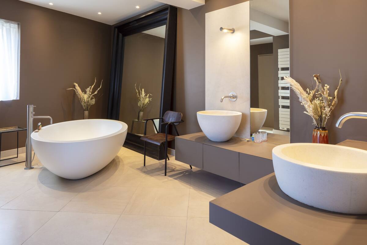 A modern bathroom with a large freestanding bathtub, a round sink, and a mirror.