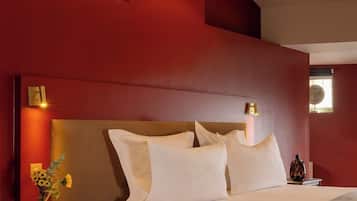 A hotel room with a large bed, a nightstand, a vase with flowers, and a ceiling light fixture.