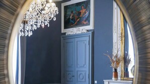 A room with a blue wall, a white door, a yellow armchair, a round table, a chandelier, and a fireplace. - Margaret - Hôtel Chouleur (Nîmes)