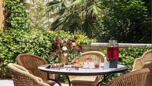 A round outdoor table with wicker chairs, a magazine, a fruit bowl, and a drink. - Margaret - Hôtel Chouleur (Nîmes)