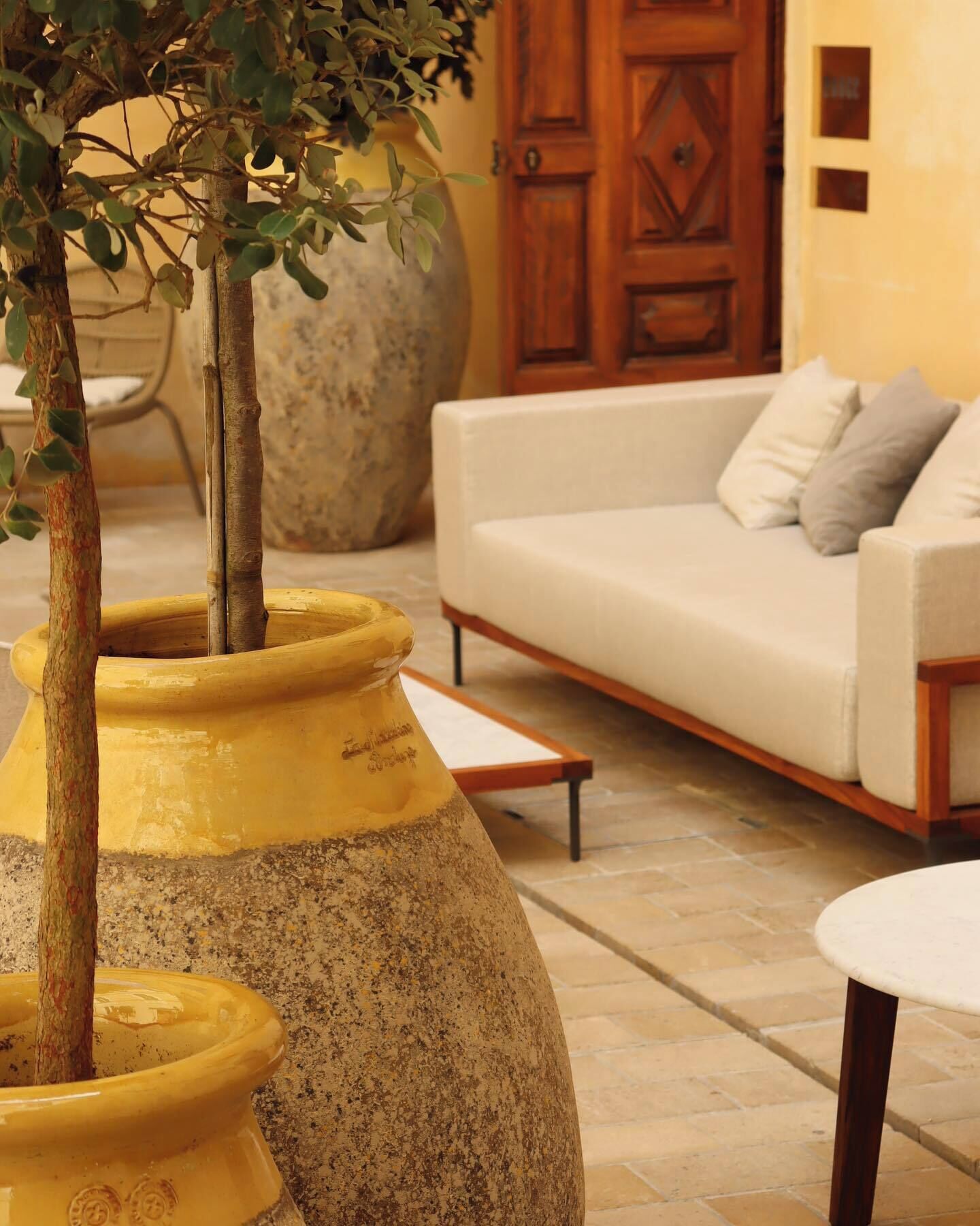 A room with a large stone planter, a white sofa, and a wooden door.