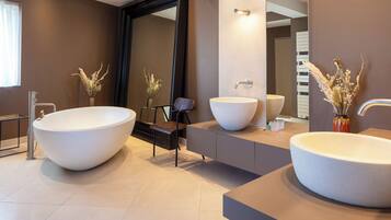 Un baño moderno con dos lavamanos grandes independientes, un espejo y plantas decorativas.