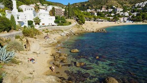 A coastal hotel with white architecture, a sandy beach, clear blue water, and rocky shoreline. - VILLA MARGARIT (Rosas / Roses)