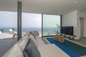 Un salon moderne doté d’une grande porte vitrée donnant sur un balcon avec vue sur la mer.