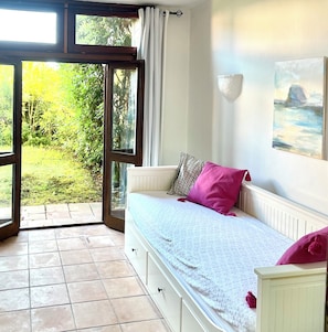 A bedroom with a bed, a view of greenery, and a painting on the wall.