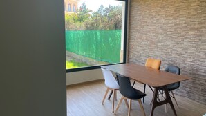 Un comedor moderno con una mesa grande, dos sillas negras y piso de madera.