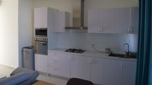 A modern kitchen with white cabinets, a built-in oven, and a gas stove.