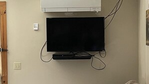 A room with a mounted flat-screen TV, a wooden door, and a patterned sofa.